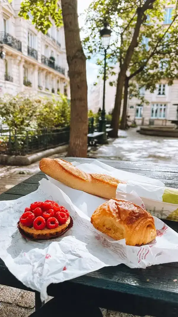 Tortinha de framboesa e croissant sobre papel, numa mesa